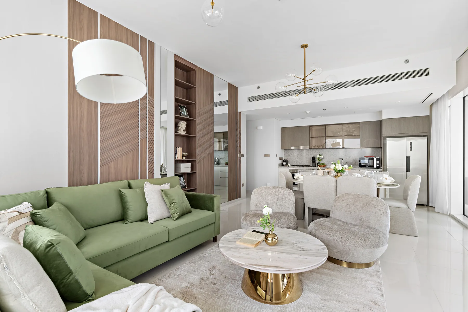 Una sala luminosa con asientos verdes y una cocina abierta.