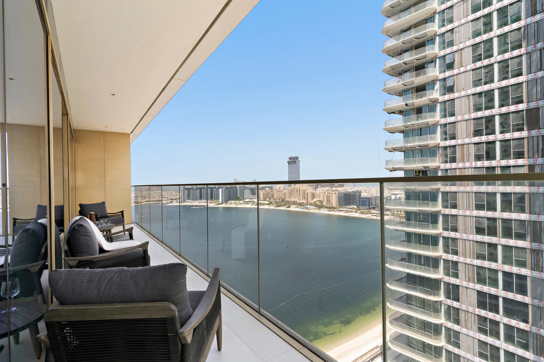 A balcony with outdoor seating overlooks the water and nearby buildings.