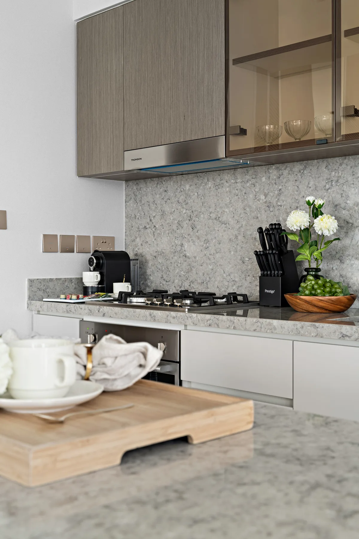 Una cocina moderna con una estufa, aparatos sobre la encimera y flores.