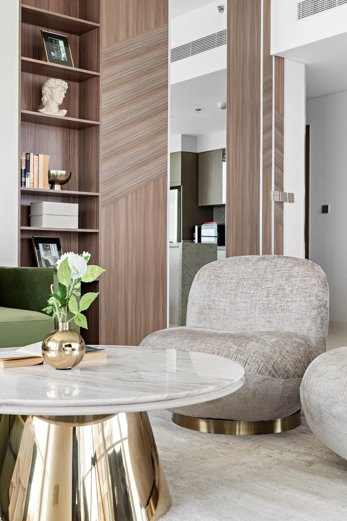 A modern living area with upholstered seating, a round table, and built-in shelving.