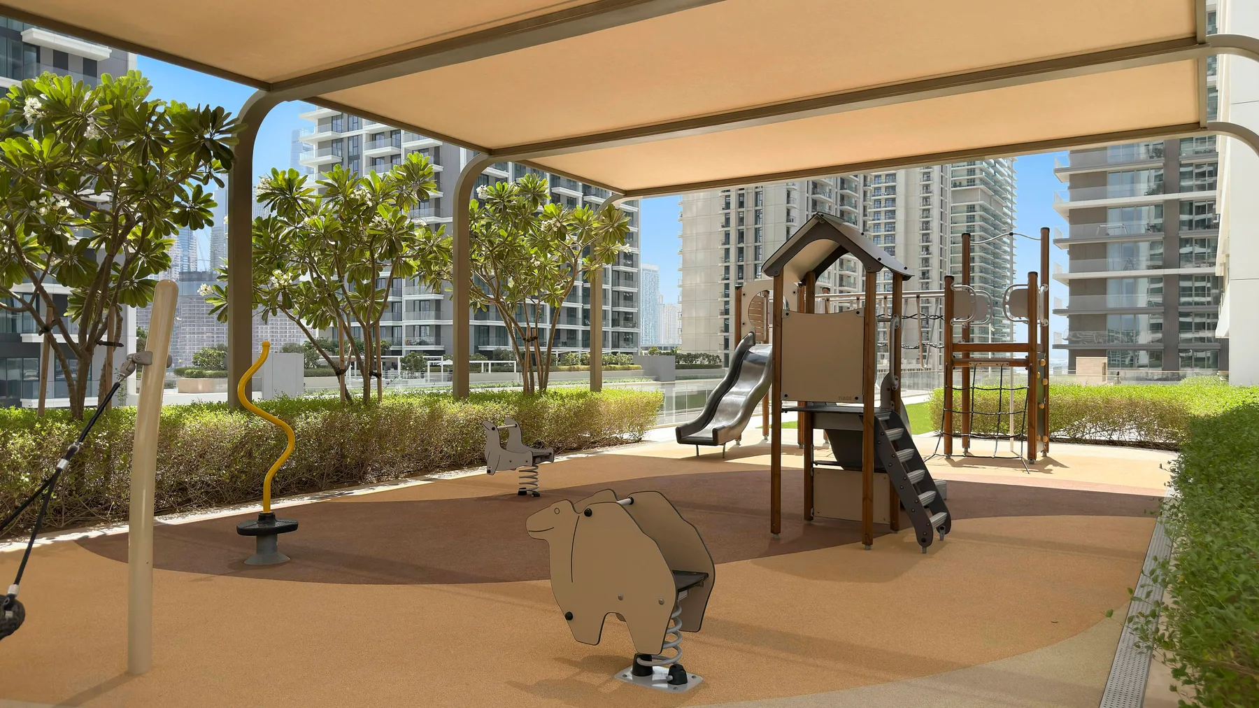 Un parque infantil sombreado cuenta con estructuras para trepar, un tobogán y un balancín con resorte.