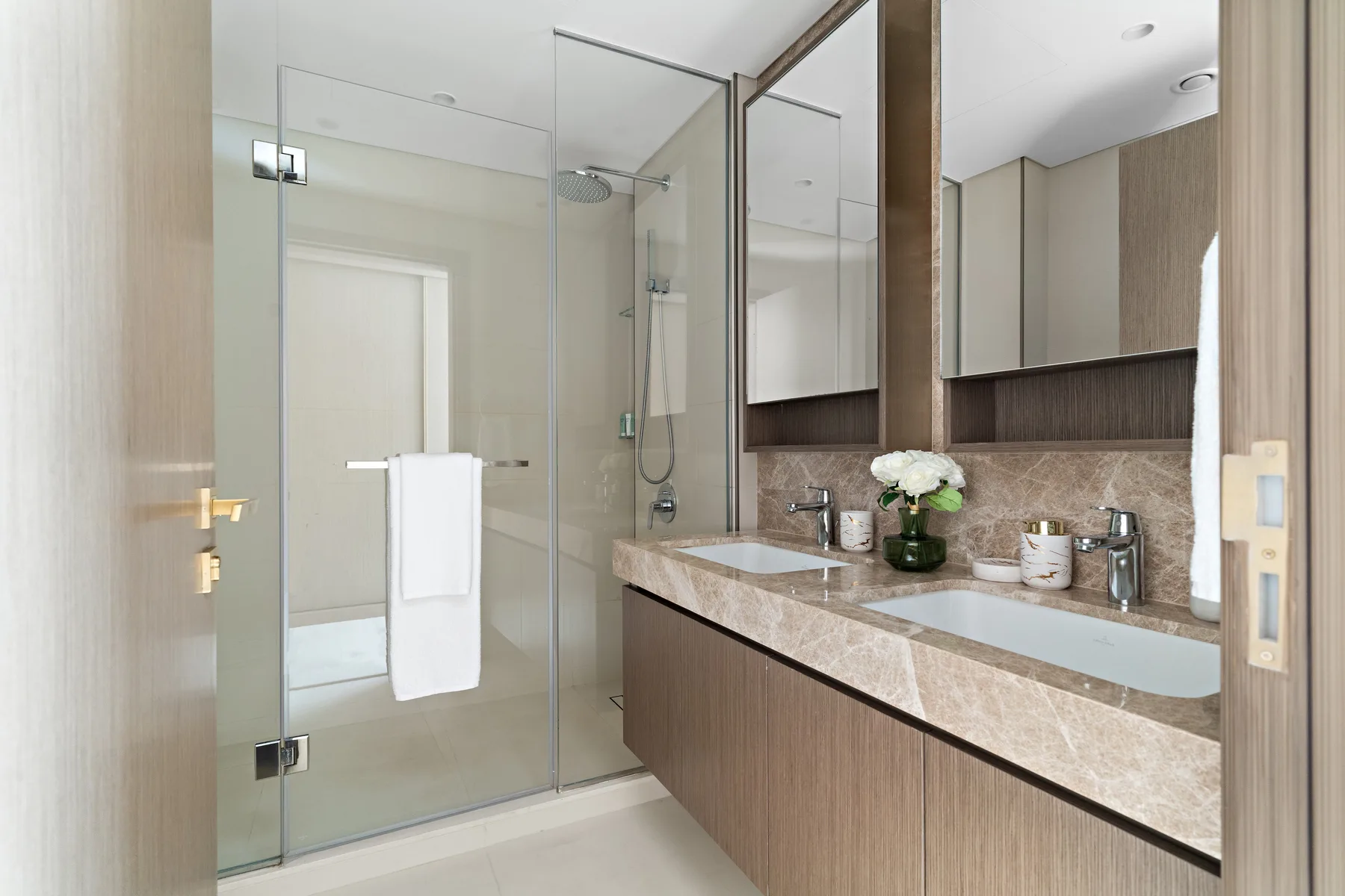 Un baño moderno cuenta con una ducha de vidrio y un largo tocador con lavabos.