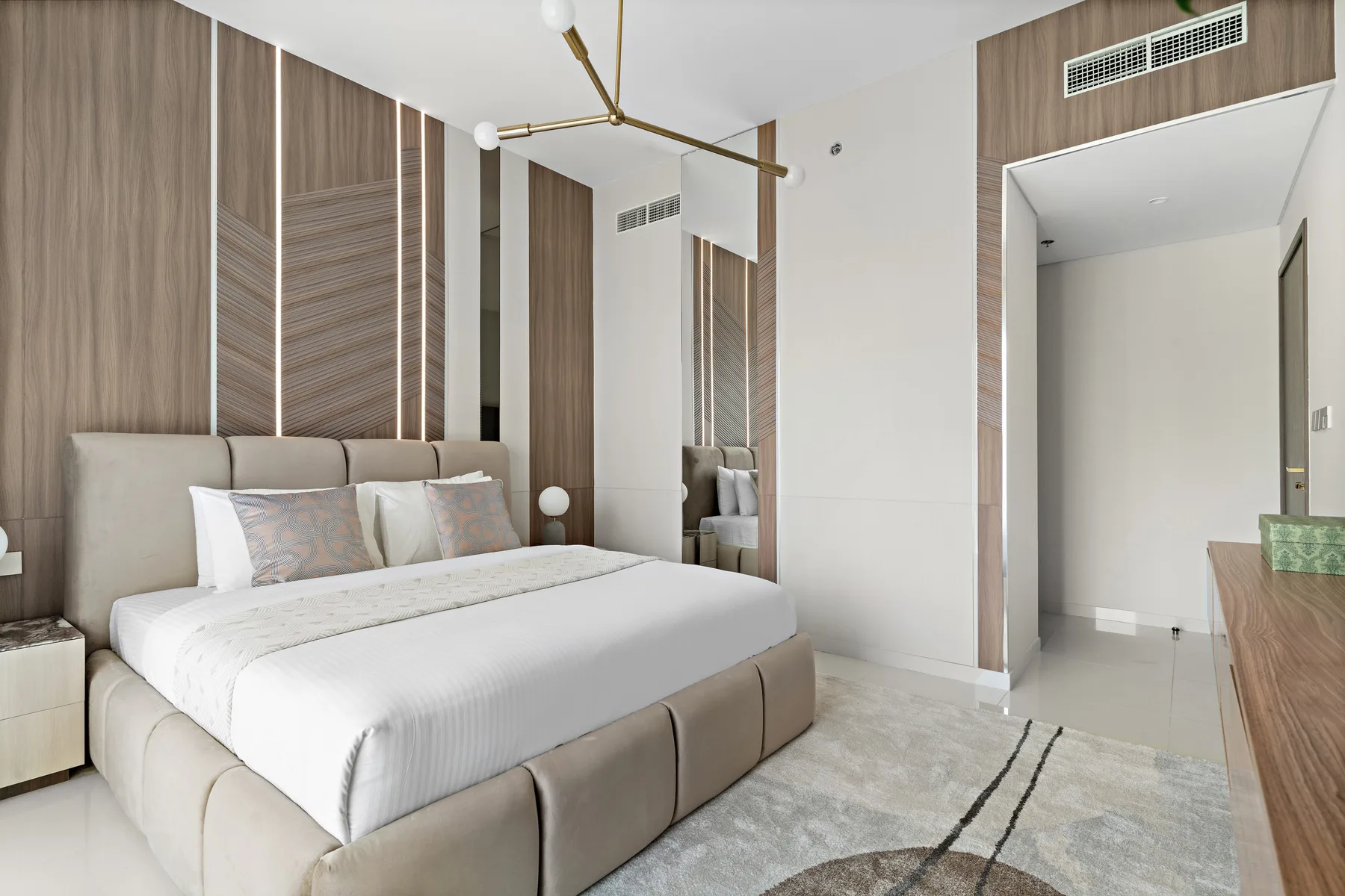 Un dormitorio moderno con una cama grande, paredes revestidas de madera y una alfombra clara.