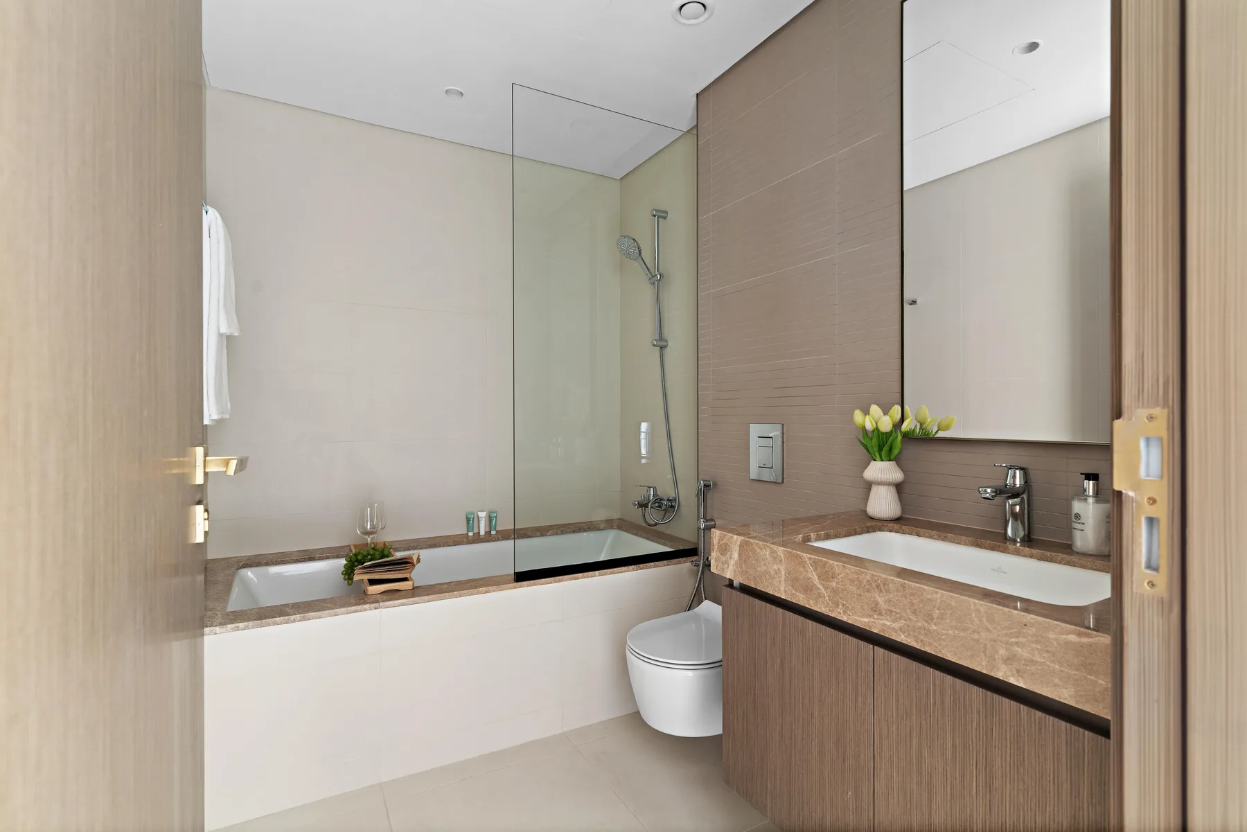 Un baño moderno con bañera, mampara de ducha de vidrio y tocador.