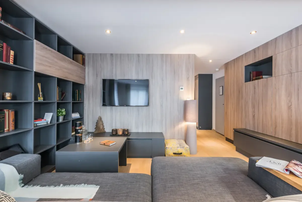 Una sala de estar moderna con televisión, estanterías y asientos.