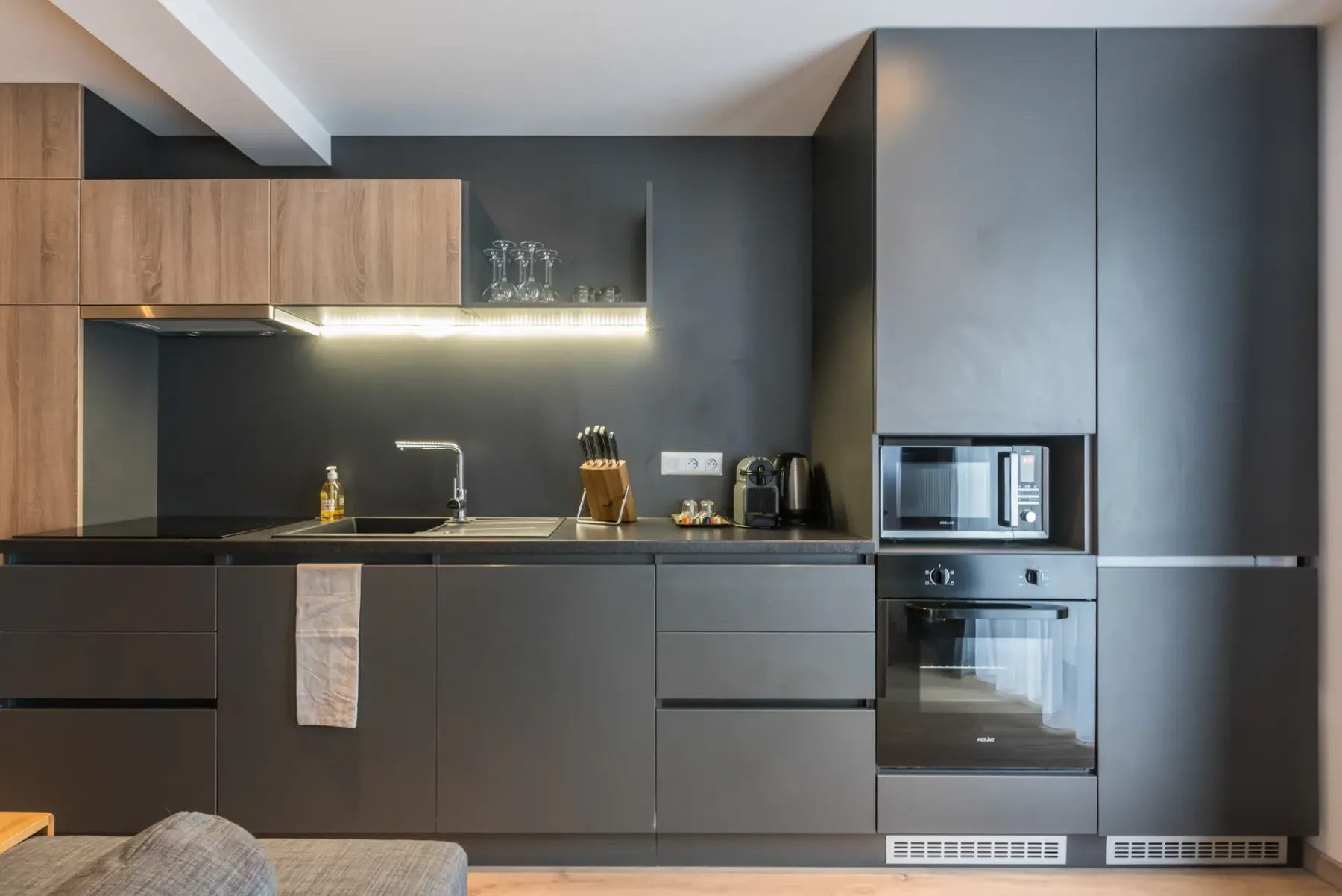 Una cocina moderna con gabinetes oscuros, una encimera y electrodomésticos integrados.