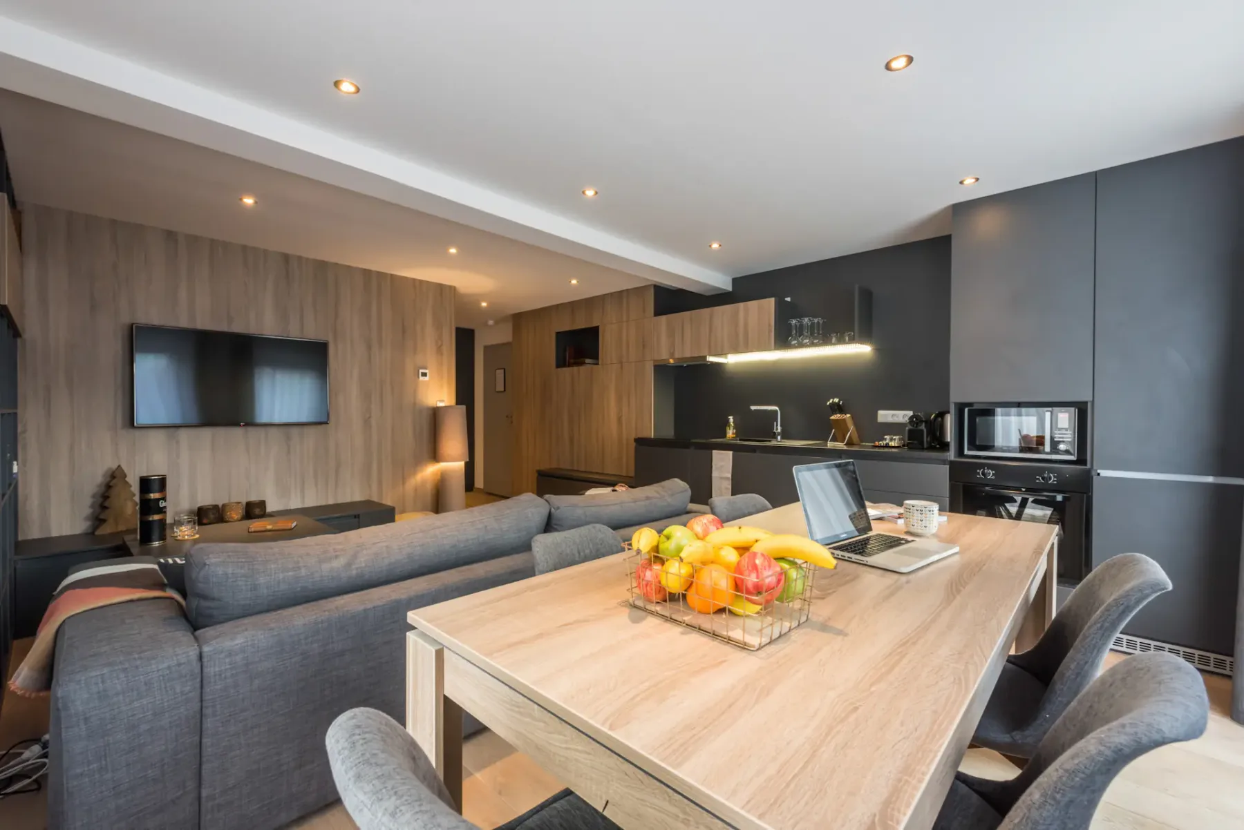 Sala de estar y comedor de concepto abierto con televisor y cocina.