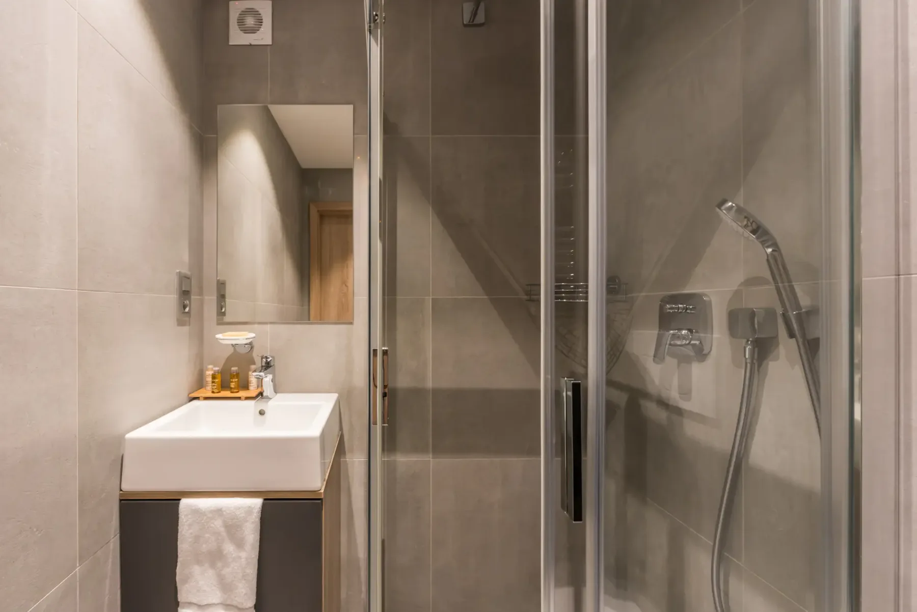 Un baño con lavabo y ducha con mampara de vidrio.