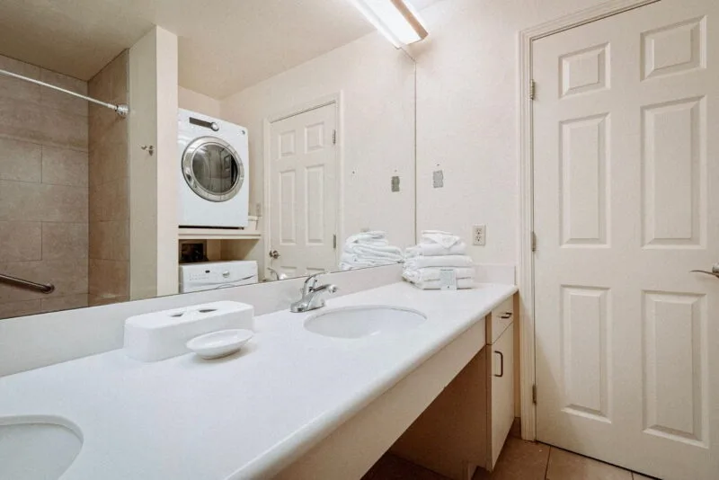 Baño con zona de lavabo doble y lavadora y secadora dentro de la unidad