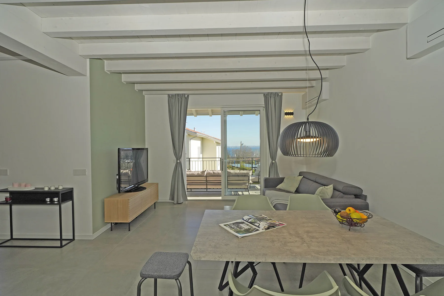 A modern living room with a dining table and sliding glass doors opening onto a balcony.
