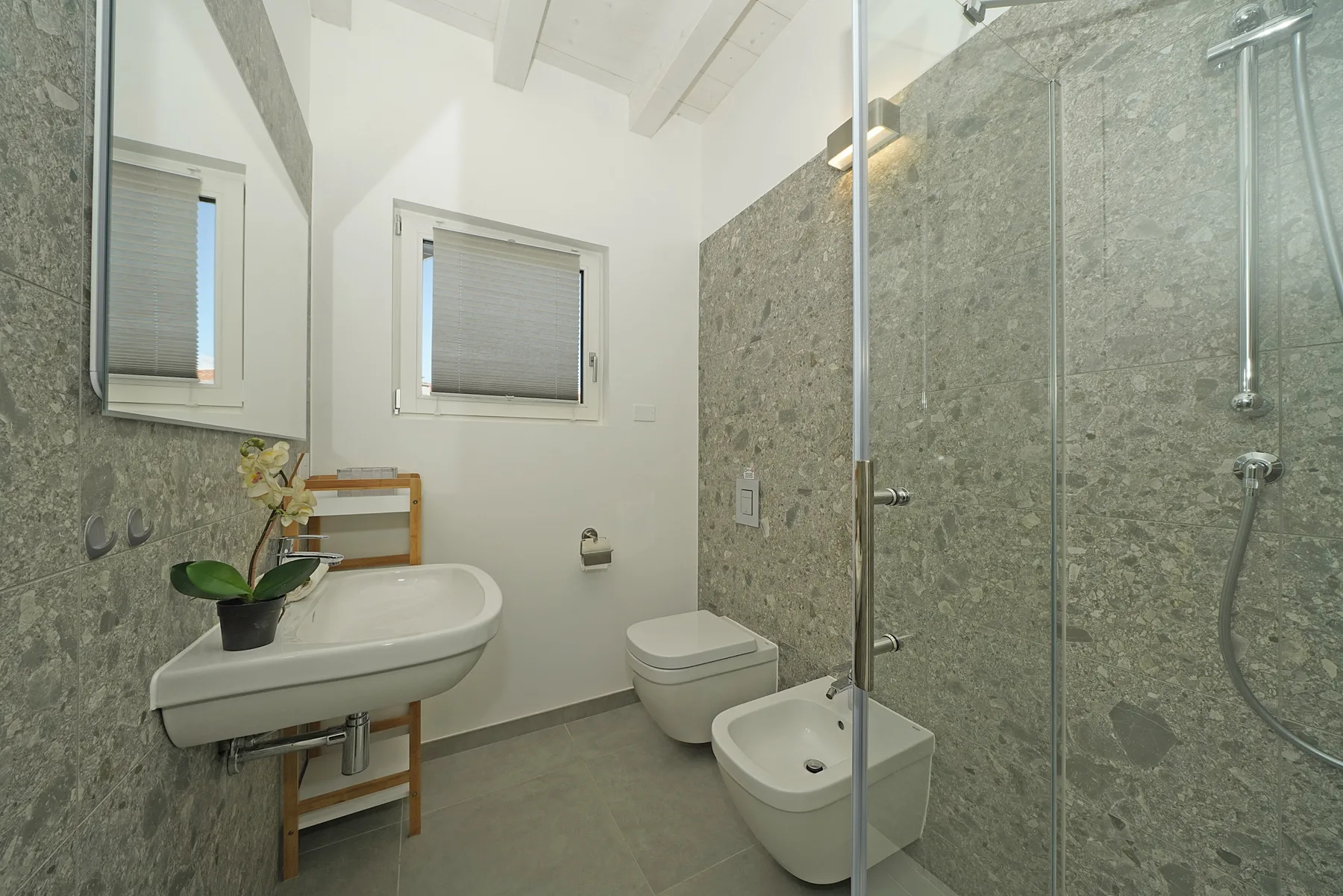 A bathroom with a sink, toilet, bidet, and glass shower.