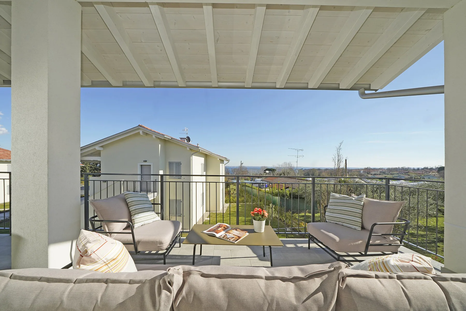 A covered outdoor terrace has seating around a low table overlooking the landscape.
