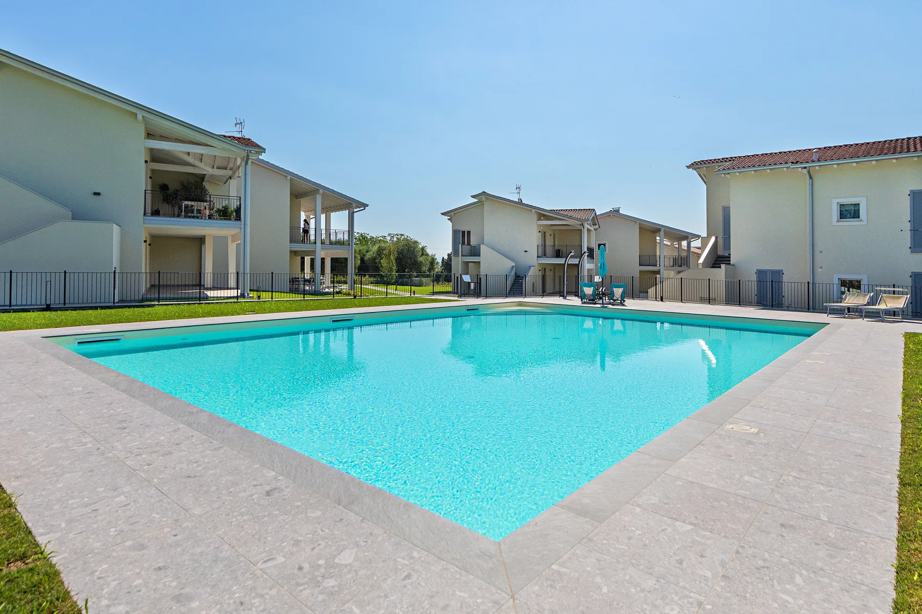 A swimming pool sits in a paved courtyard beside several residential buildings.