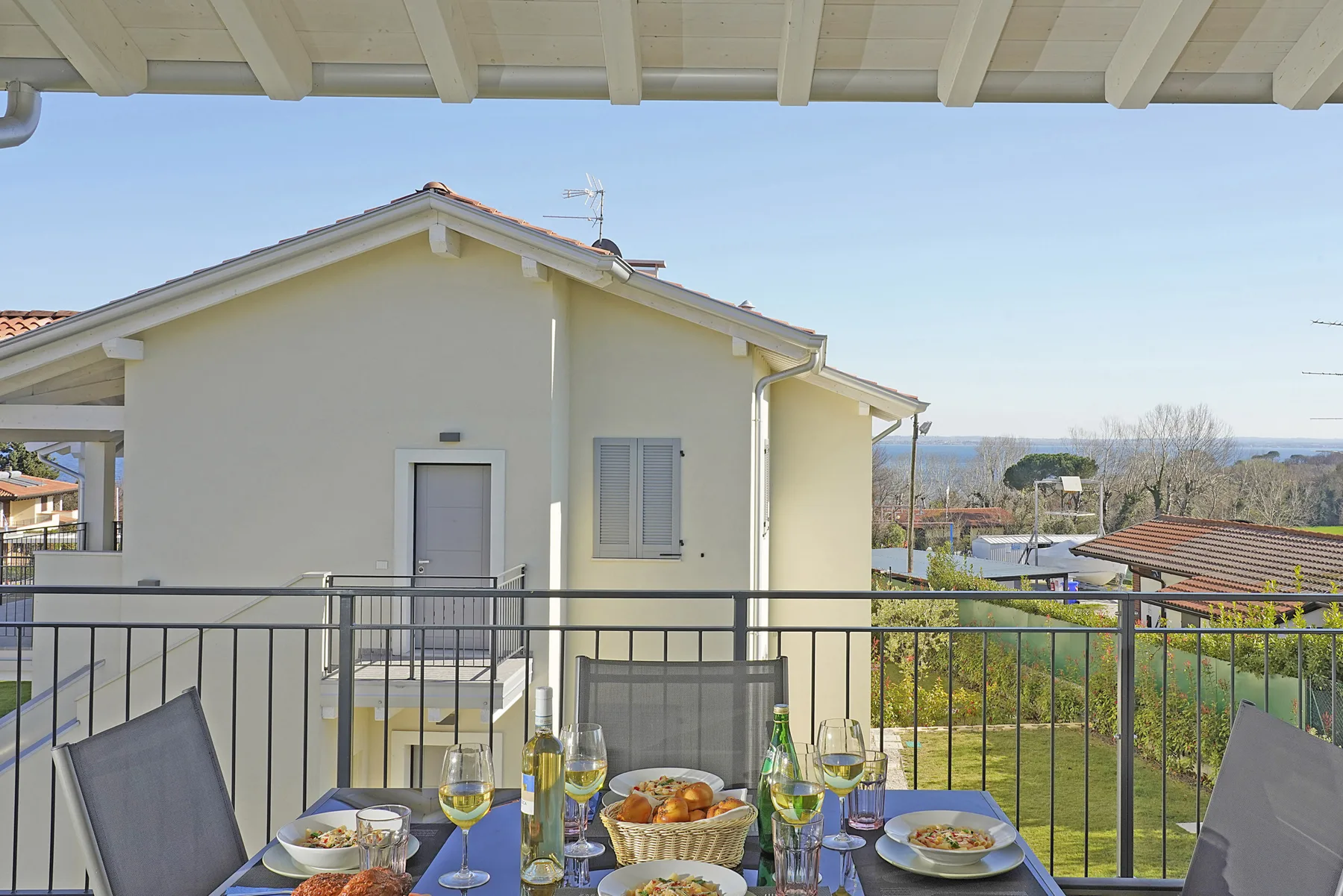 A terrace dining area overlooks a pale house and the surrounding landscape.