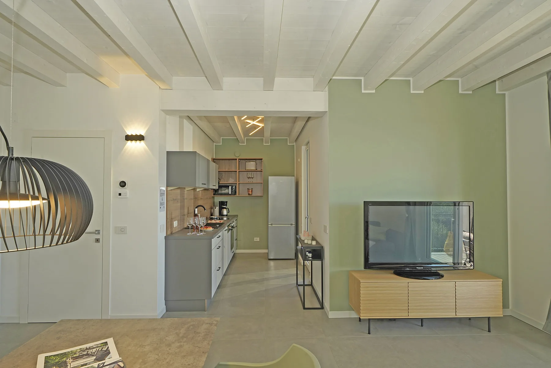 A living area with a television beside an open kitchen.