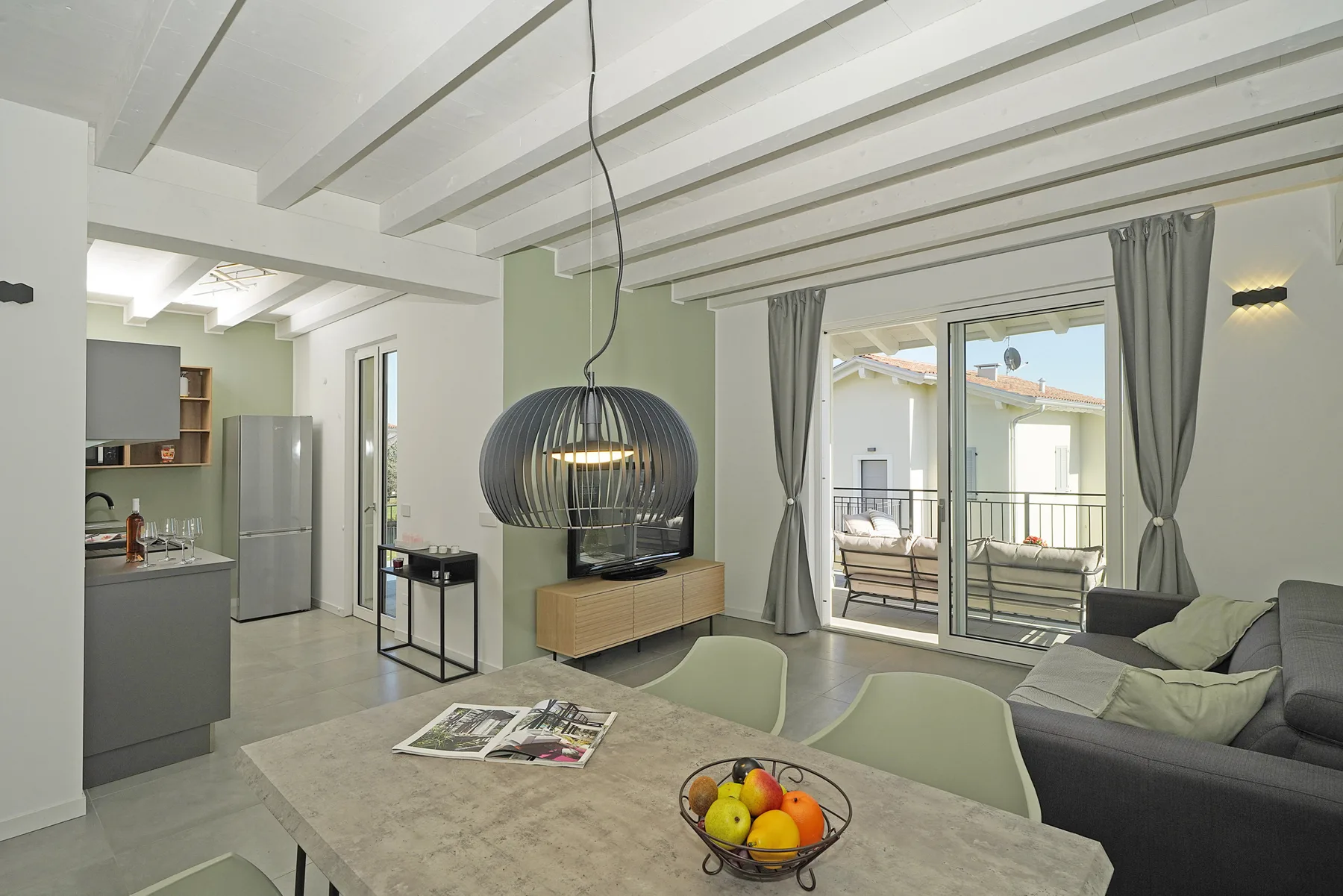 A bright open-plan living area with a kitchen, dining table, and sofa.