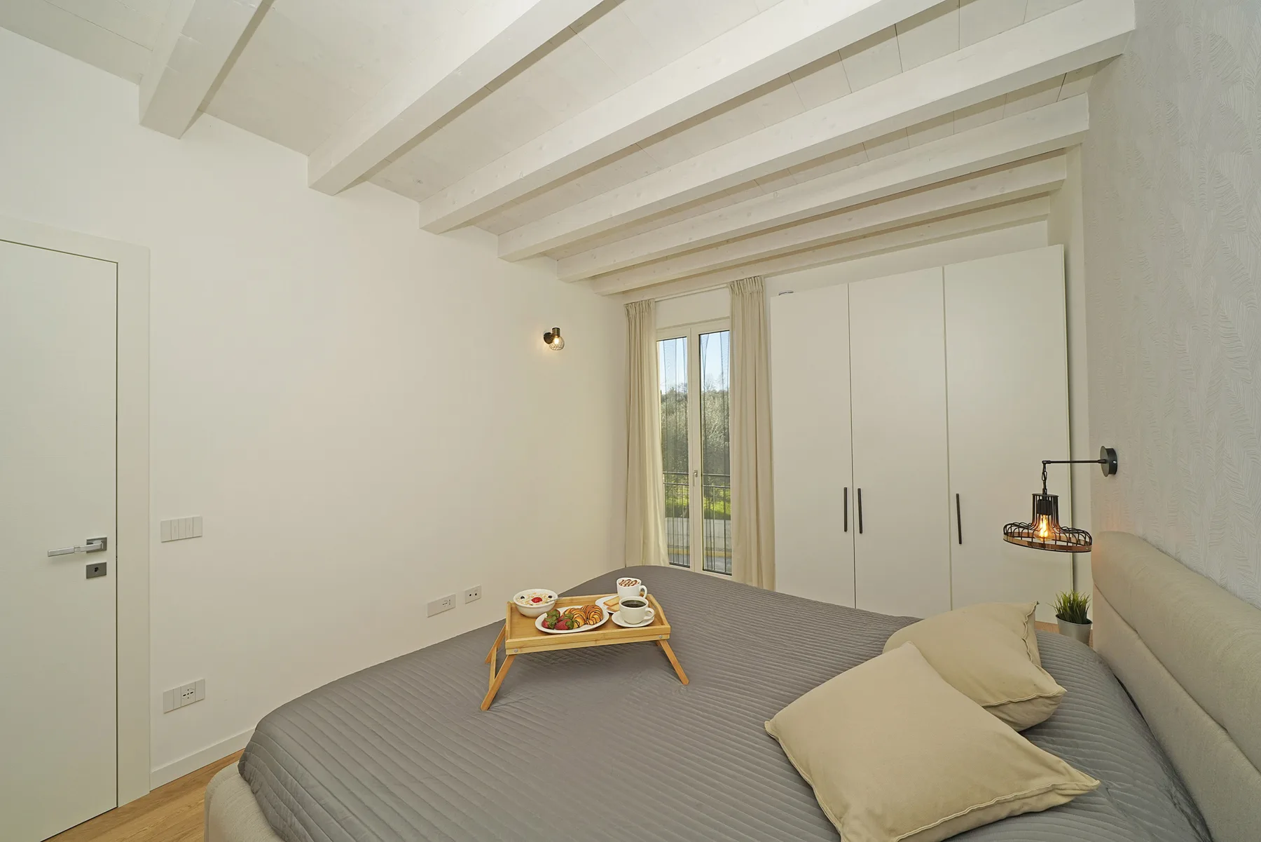 A bedroom with a gray bed and a white wardrobe.