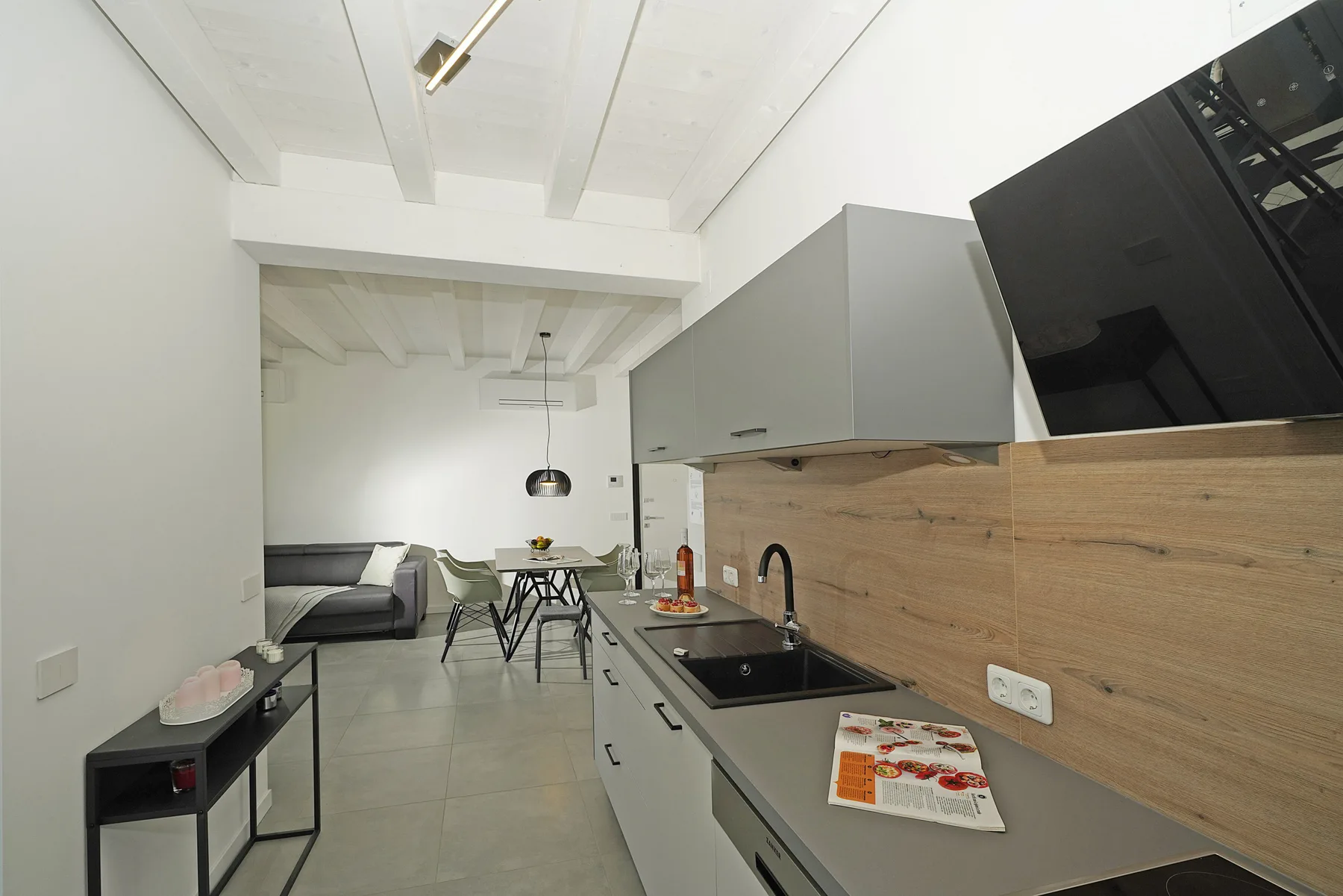 A modern kitchen opens into a dining area, with a counter and table.