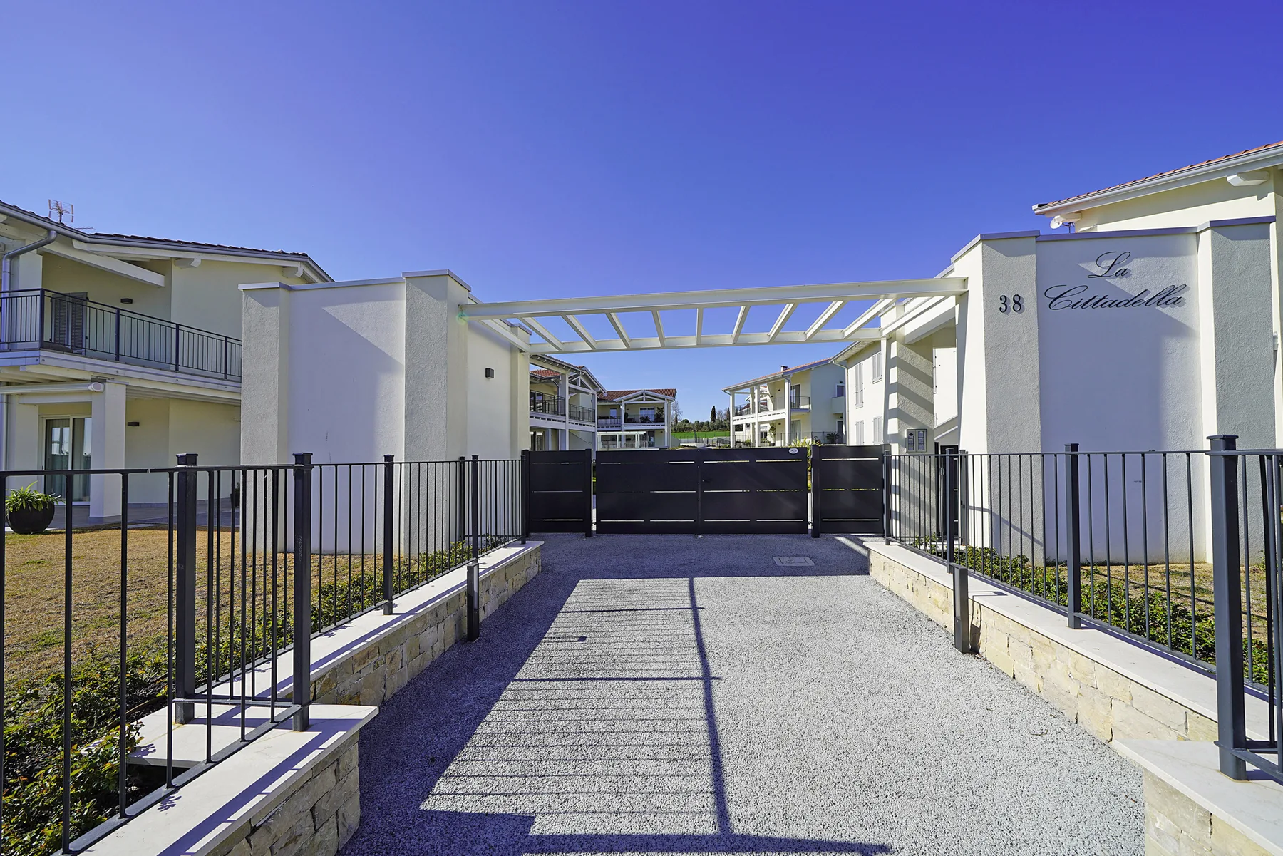 A gated entrance and paved driveway lead between modern residential buildings.