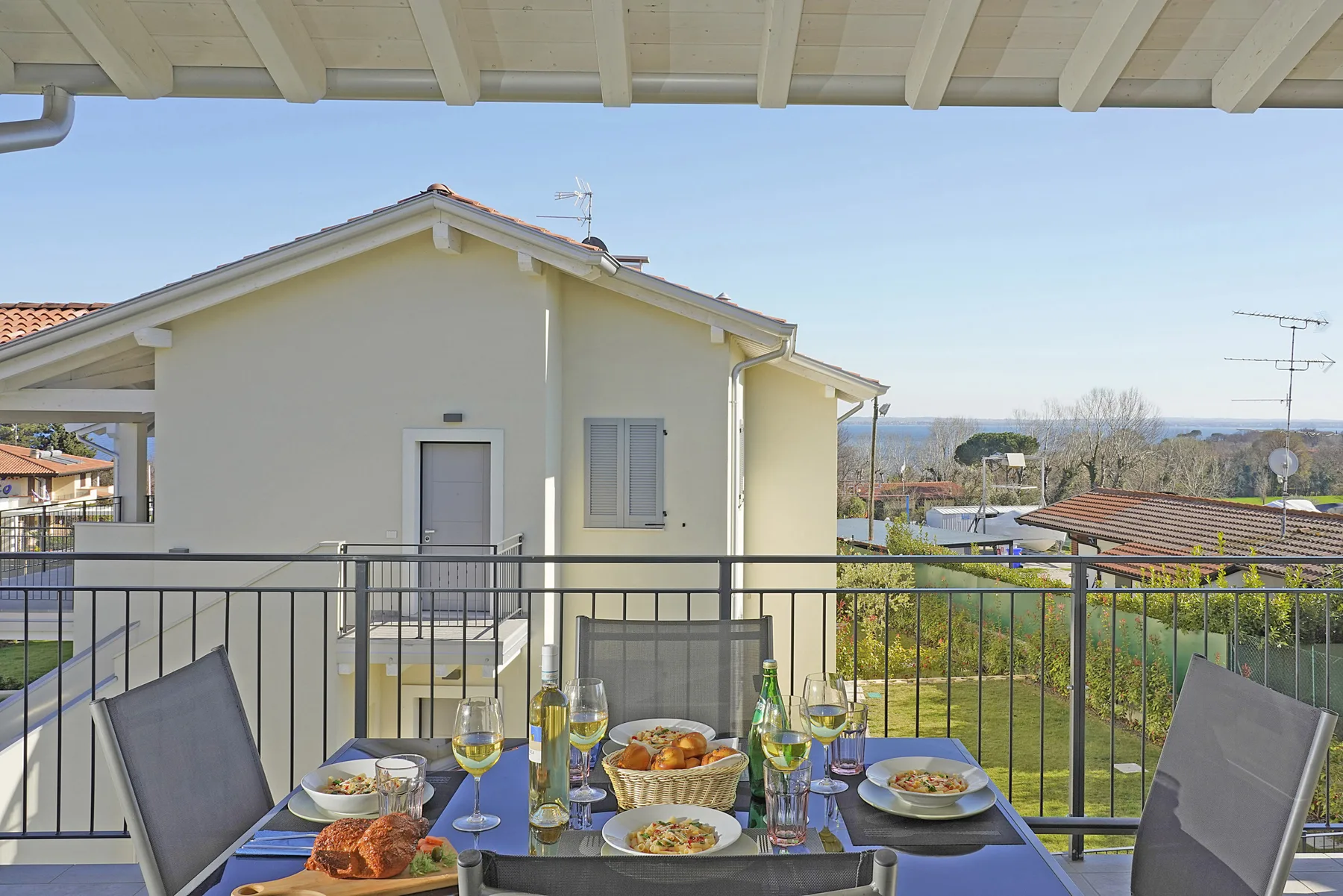 An outdoor dining area overlooks a garden and neighboring houses.
