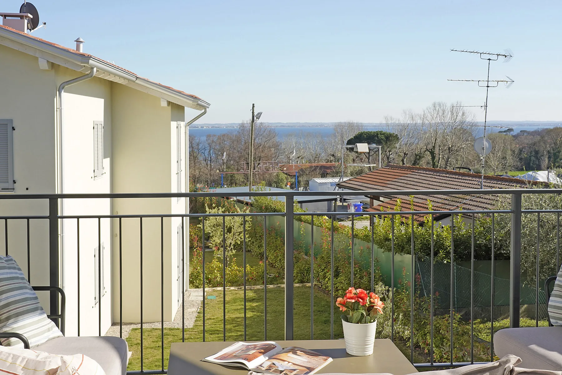 A balcony seating area overlooks gardens and distant water.