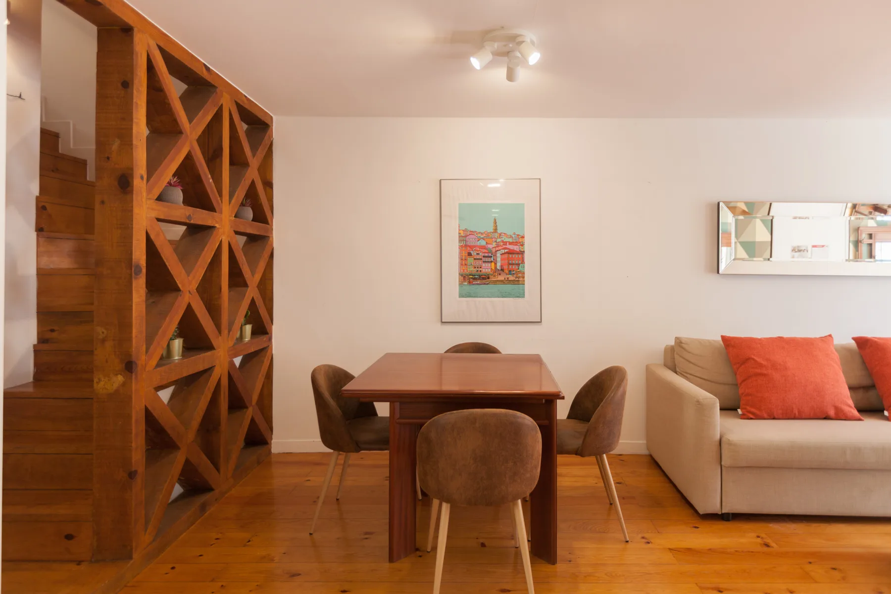 Un comedor con una mesa de madera está junto a una zona de estar con sofá.