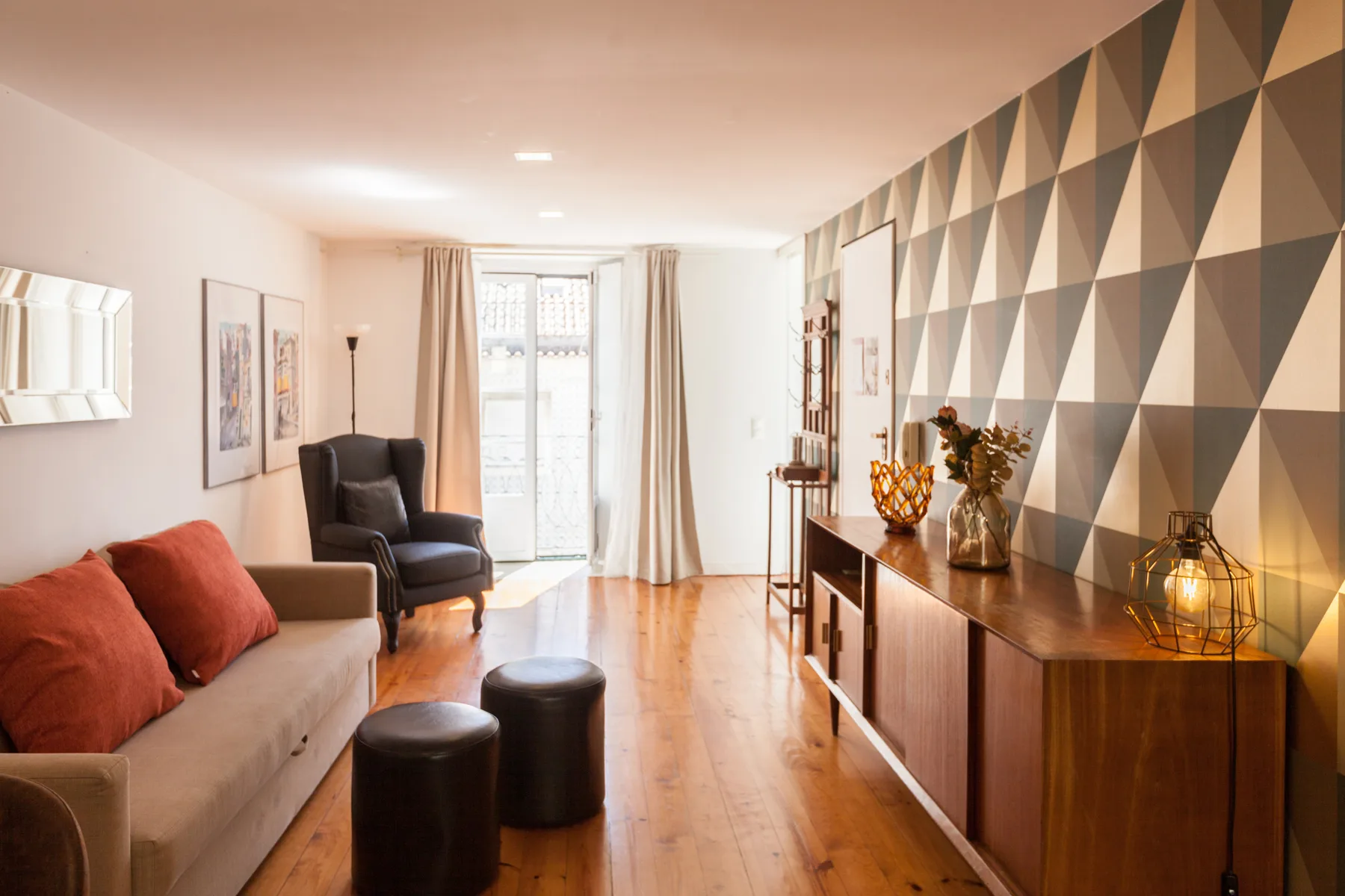Una sala de estar con asientos, una consola de madera y una pared con motivos geométricos.