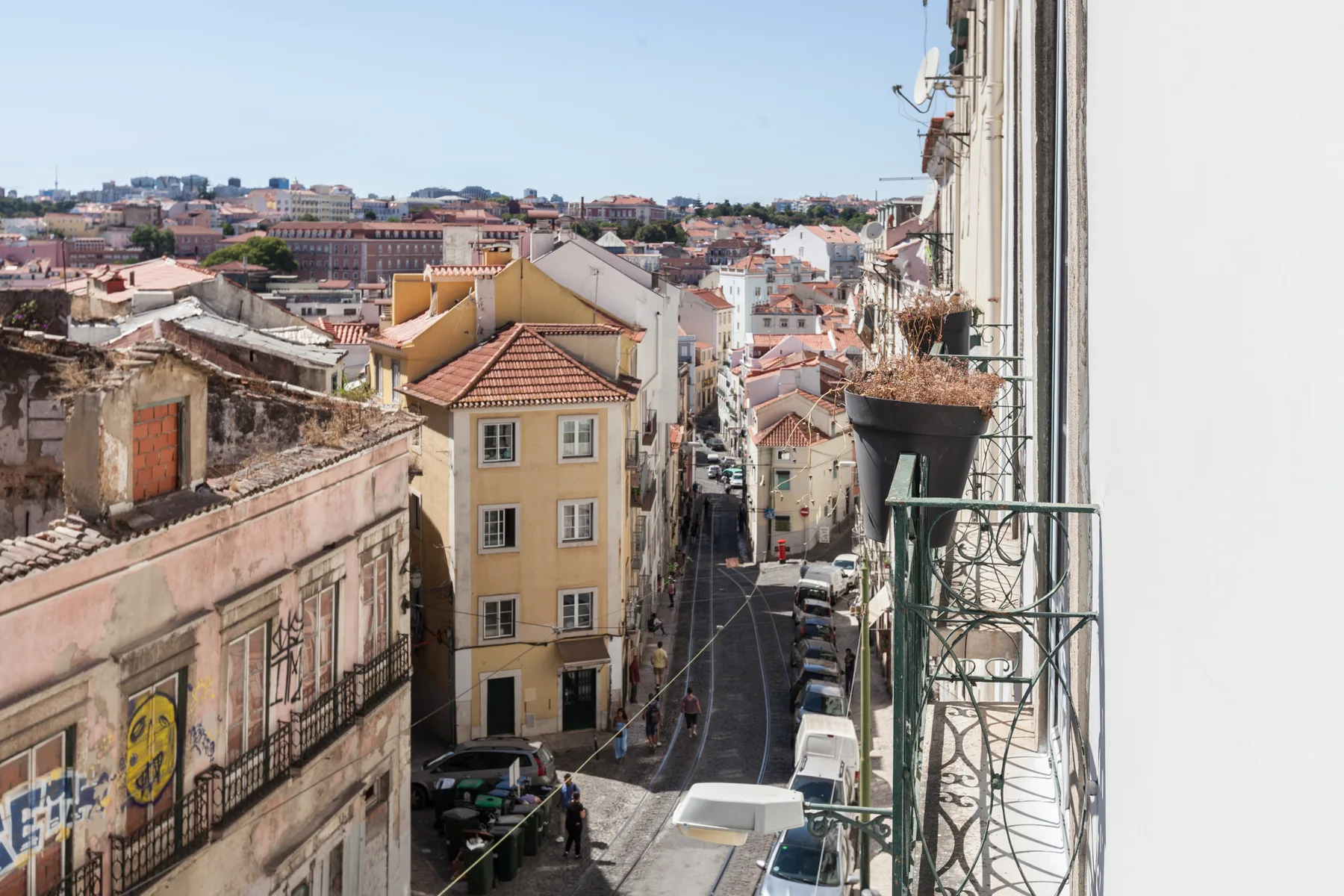 Desde un balcón se ven una calle de la ciudad y los tejados cercanos.