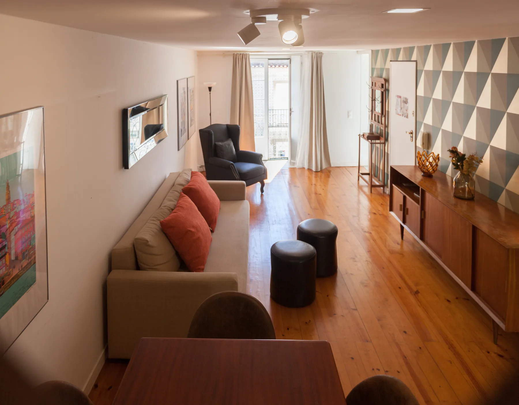 Una sala de estar con asientos, una mesa baja y un suelo de madera.