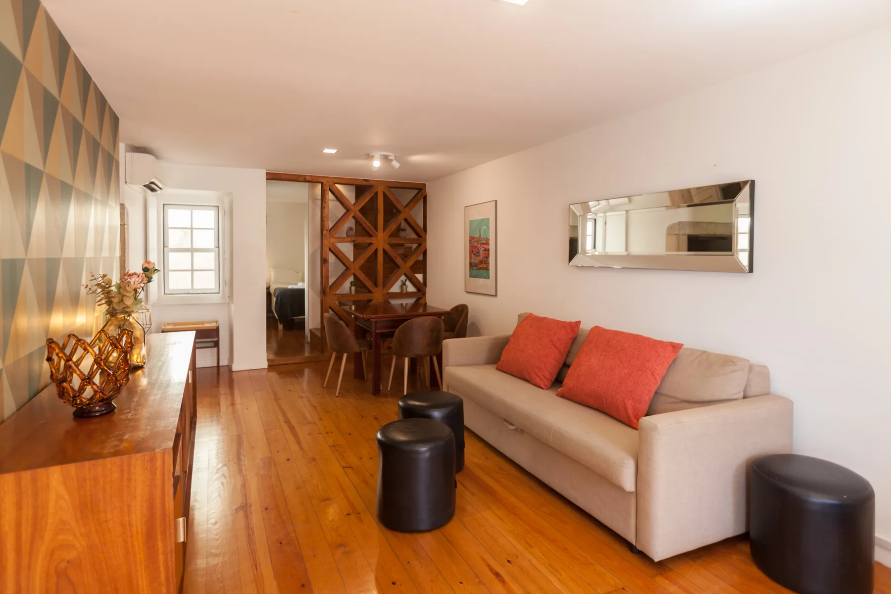 Sala de estar con un sofá beige y cojines rojos.