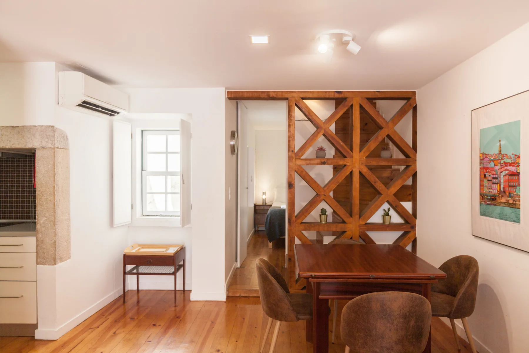 Comedor con una mesa de madera y sillas junto a un tabique decorativo de madera.