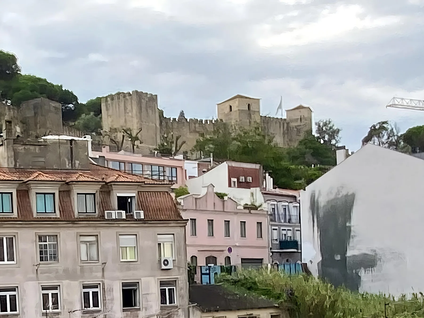 Murallas de piedra y torres históricas se alzan sobre un barrio de edificios agrupados en la ladera.