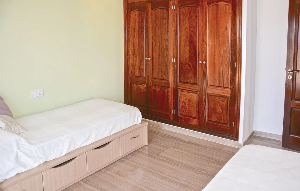 Un dormitorio con dos camas y un gran armario de madera.