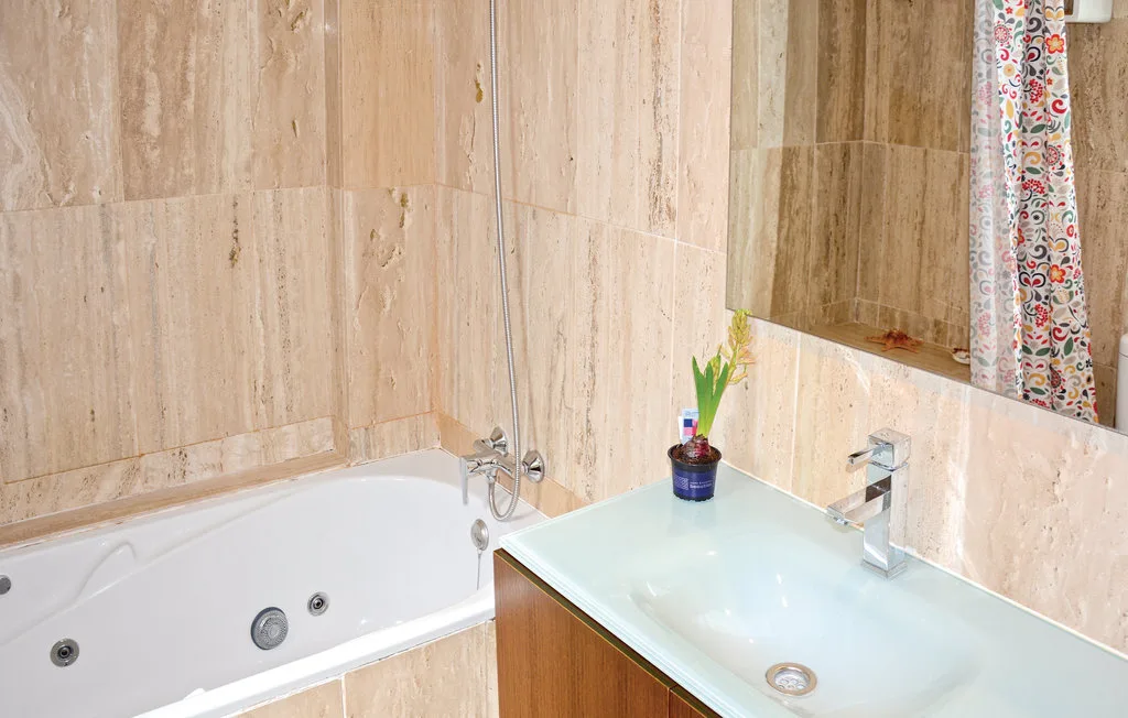 Un baño con bañera y lavabo bajo un espejo grande.