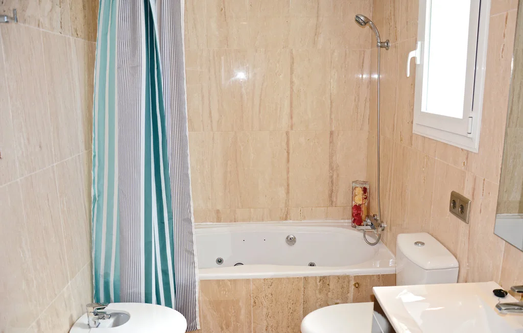 Un baño alicatado con bañera, ducha y lavabo.