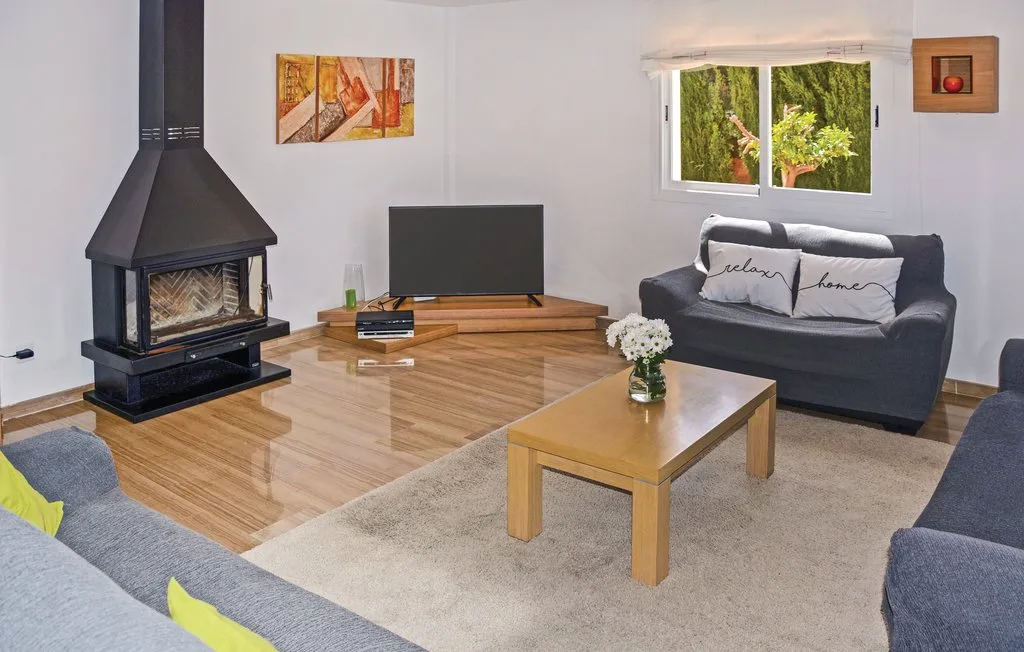 Una sala de estar con asientos, una mesa de centro, televisor y chimenea.