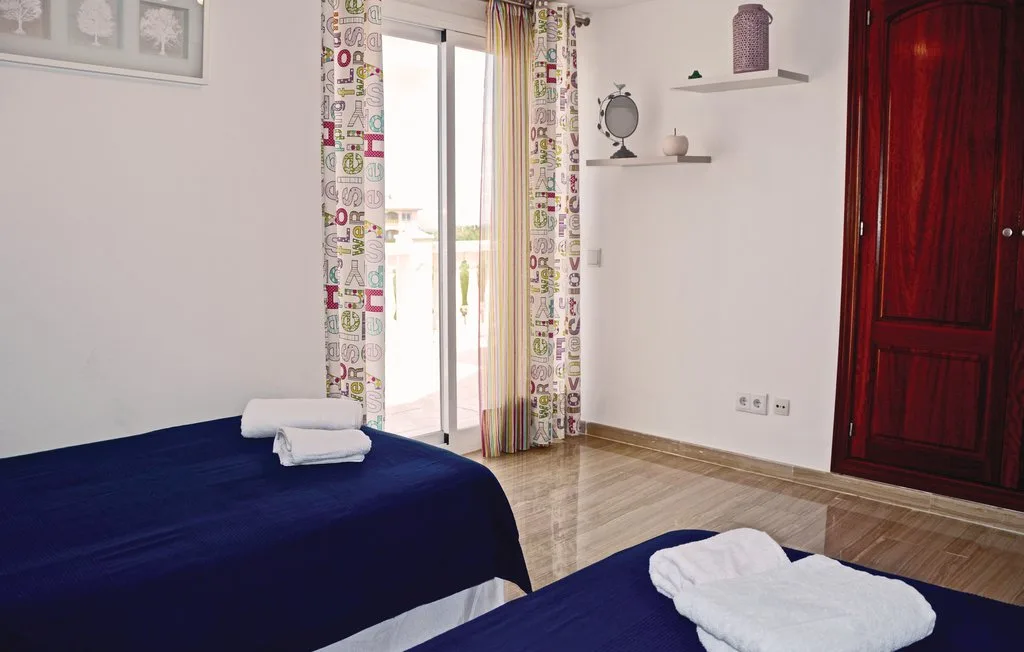 Un dormitorio con camas cubiertas de ropa de cama azul oscuro y toallas.