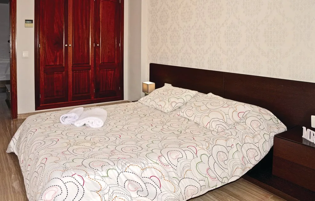 Un dormitorio con una cama grande, ropa de cama estampada y armarios de madera oscura.