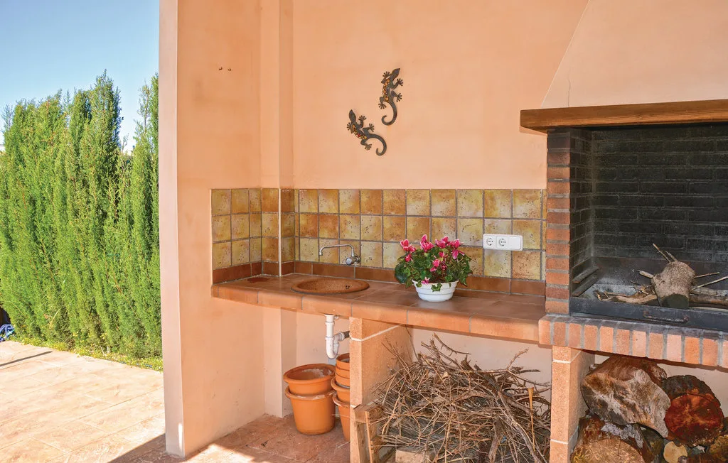 Una zona de barbacoa al aire libre con encimera de azulejos, fregadero y parrilla integrada.