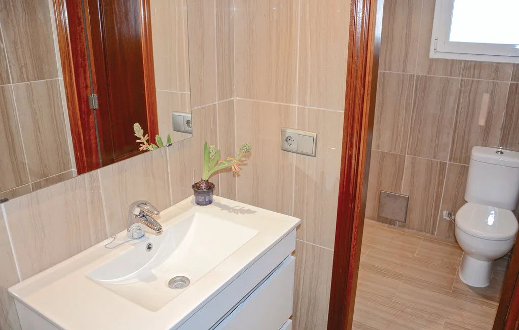 Un baño alicatado, con un lavabo en primer plano y un inodoro al fondo.