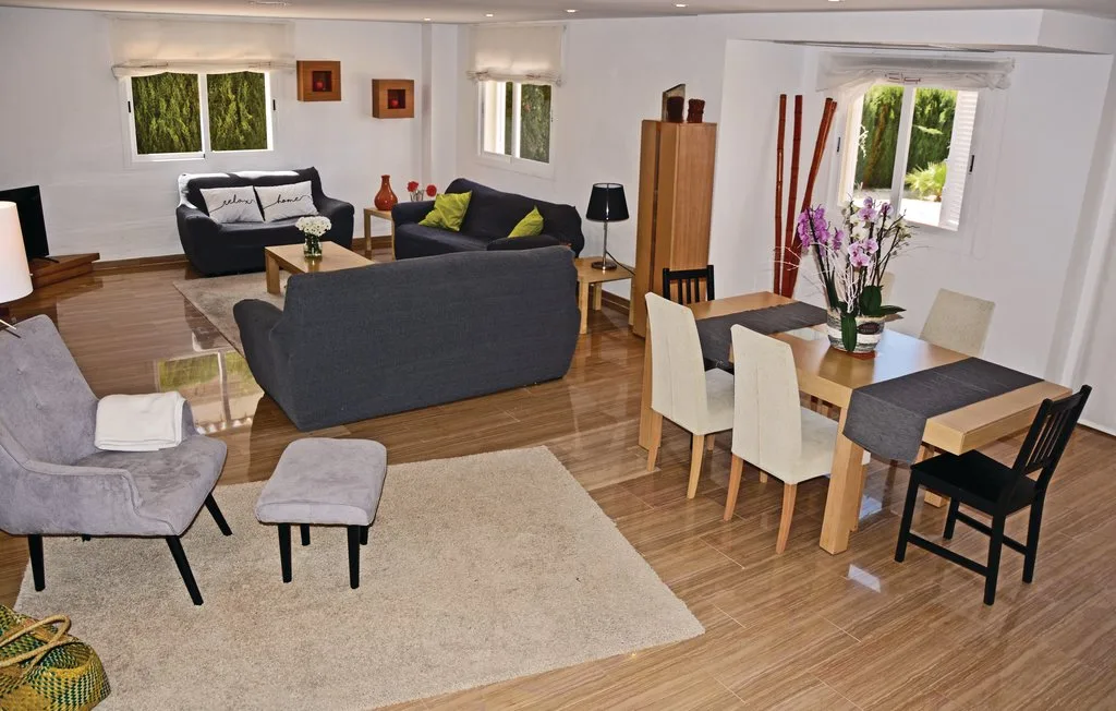 Una sala de estar y comedor con asientos, una mesa y ventanas.