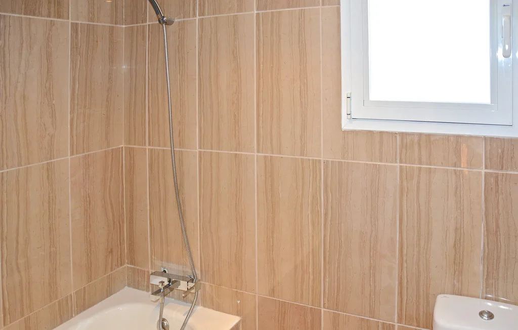 Un baño con azulejos, bañera, ducha y ventana.