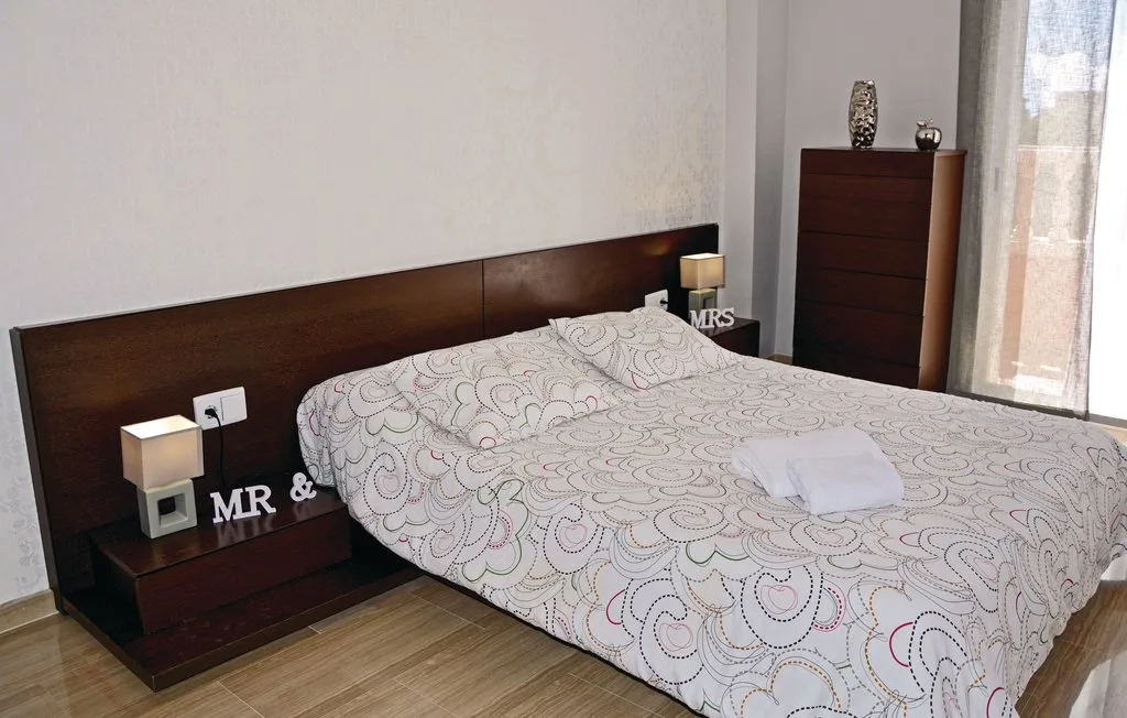 Un dormitorio con una cama cubierta con ropa de cama estampada y un cabecero oscuro.