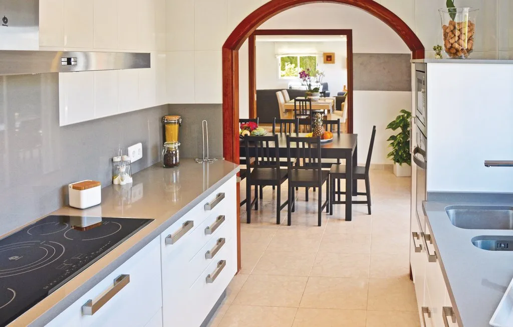 Una cocina luminosa se abre a un comedor a través de un arco.