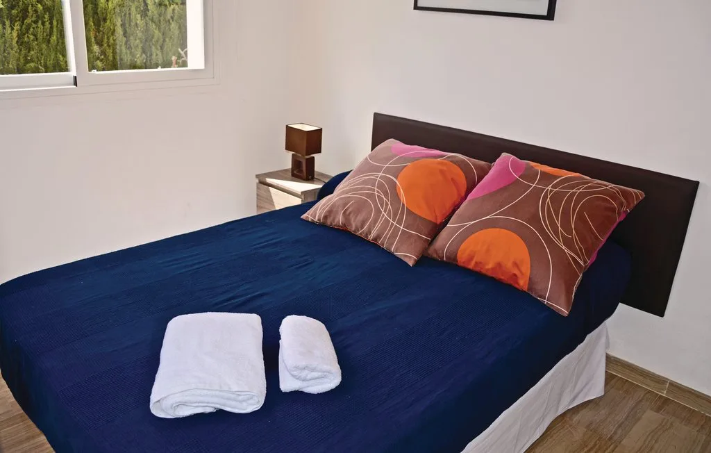 Un dormitorio con una cama vestida con ropa de cama azul oscuro y almohadas estampadas.