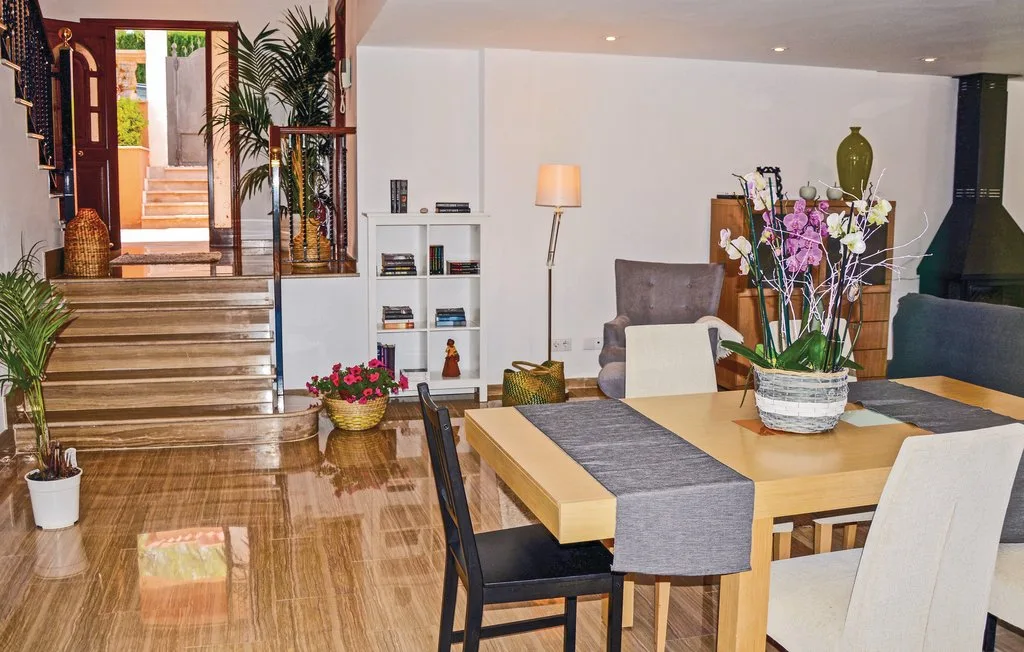 Comedor con una mesa, sillas y flores junto a una escalera.