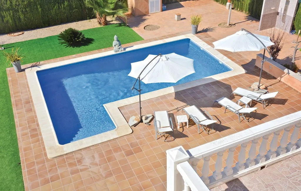 Una piscina al aire libre con sombrillas y asientos en un patio embaldosado.