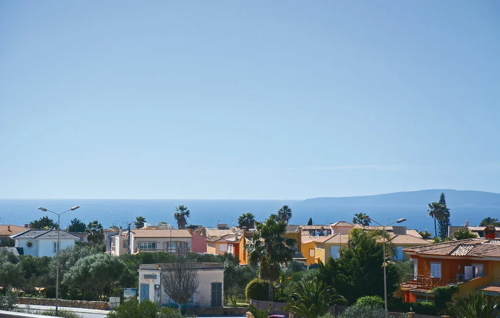 Un barrio costero con casas y árboles frente al mar.