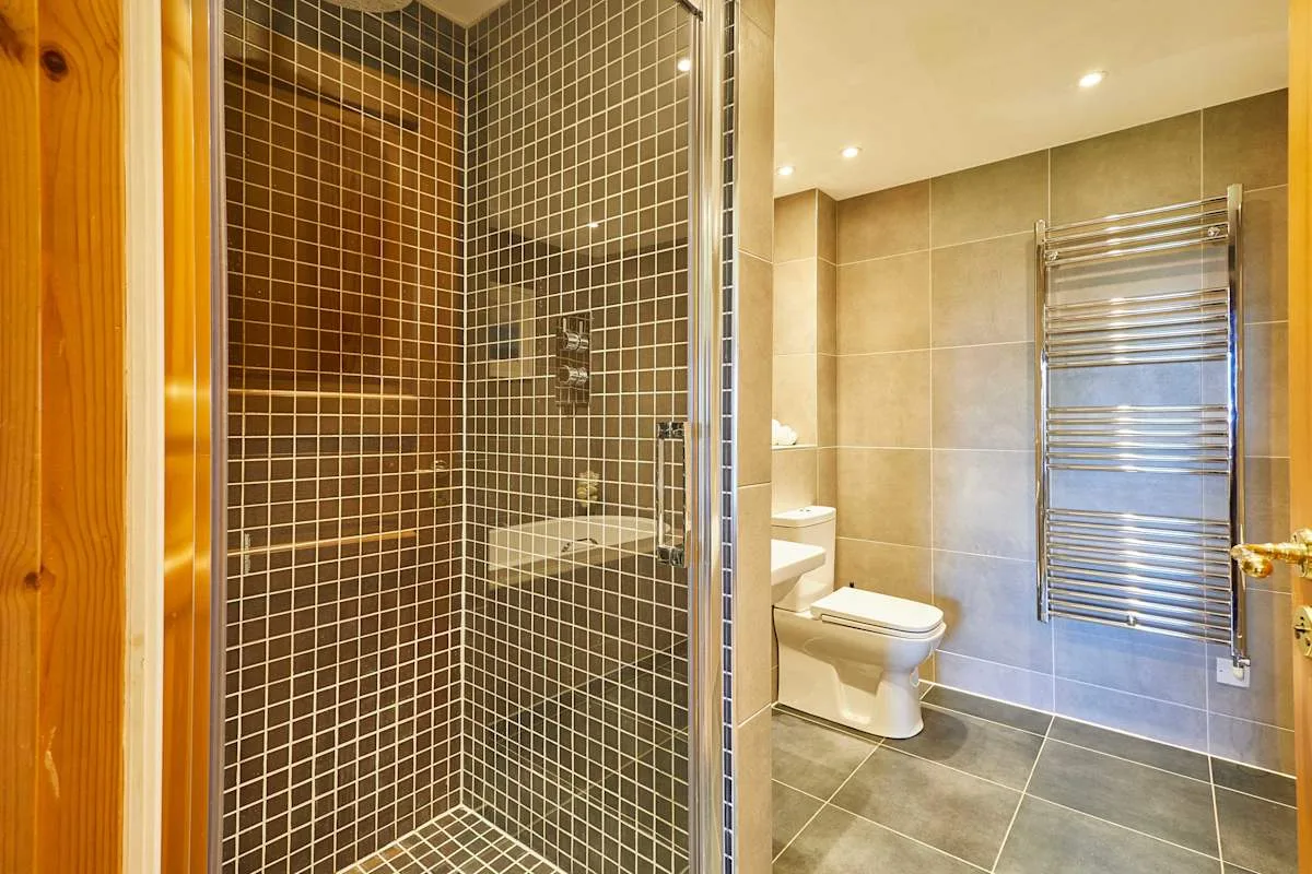 A tiled bathroom with a glass shower and a towel warmer.