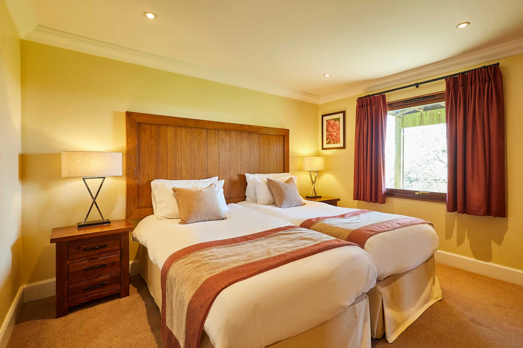 A bedroom with two beds, a wooden headboard, and a window with curtains.